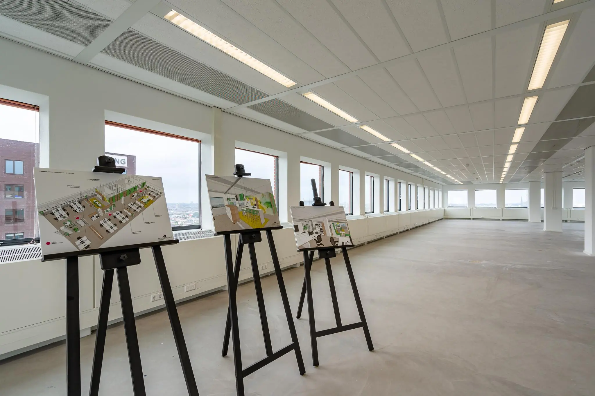 Lege kantoorruimte aan het Johanna Westerdijkplein met presentatiestandaards waarop interieurontwerpen staan.